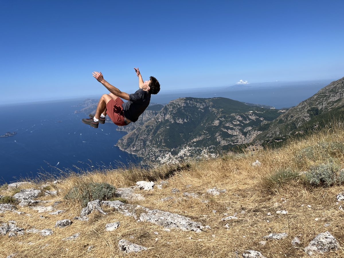 Carter mid-backflip on a clifftop high above the coast
